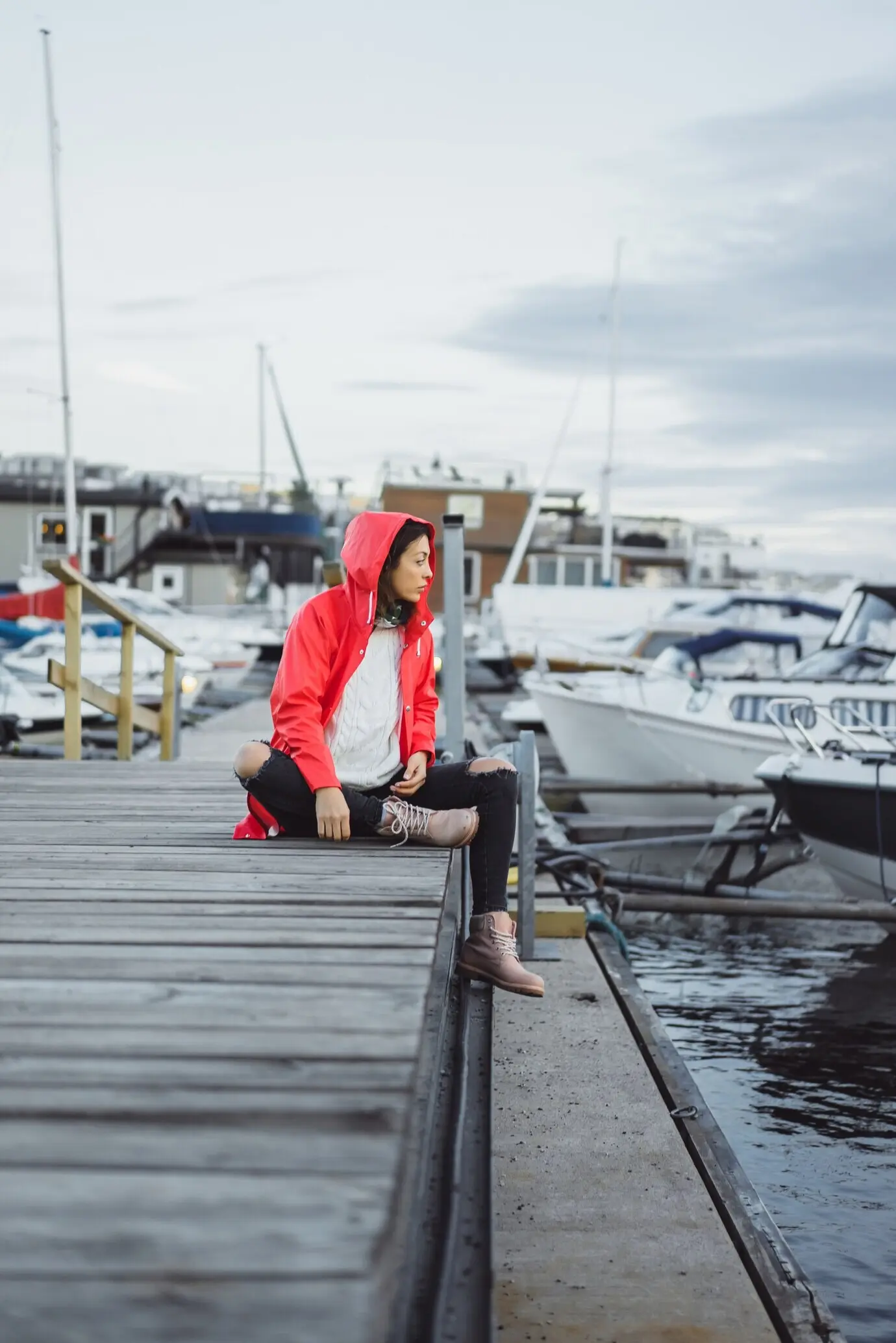 A beautiful young woman in a red cloak at the yacht port in Stockholm, Sweden.