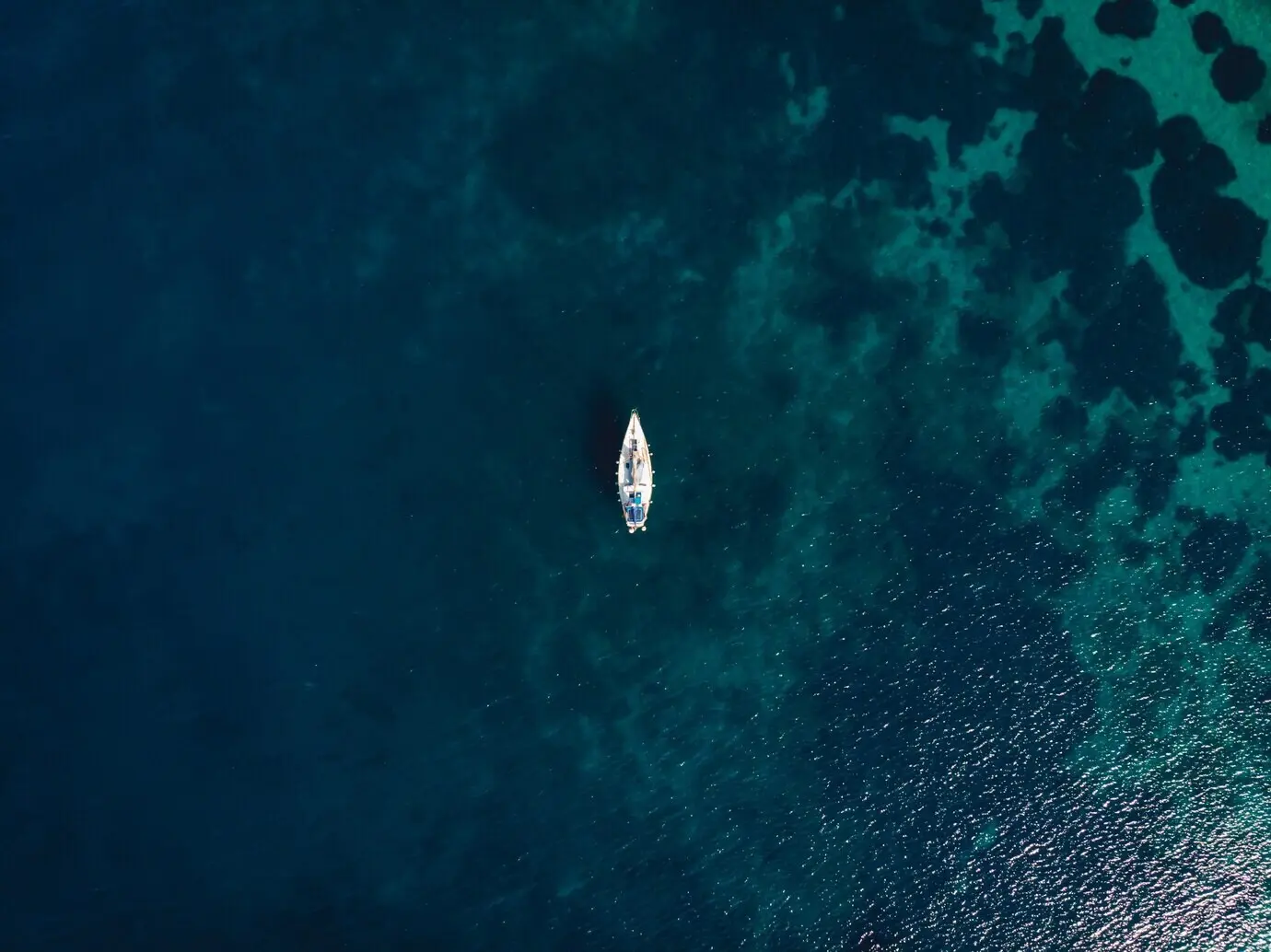 A lone boat in the middle of a clear blue sea.