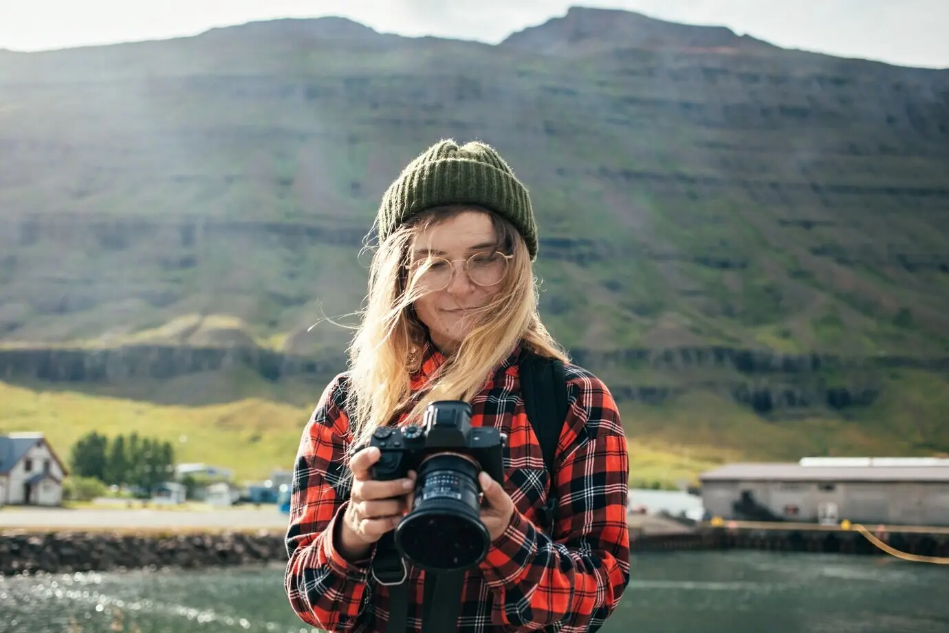 A woman takes photos of an epic cruise ship in a fjord.