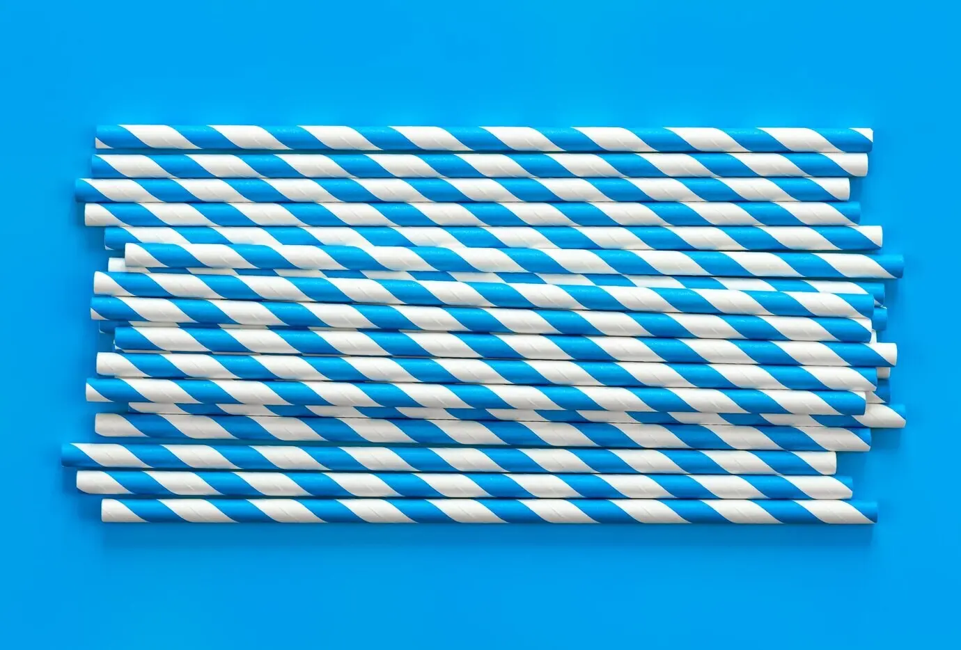 Flat lay of party drinking straws on a blue background.
